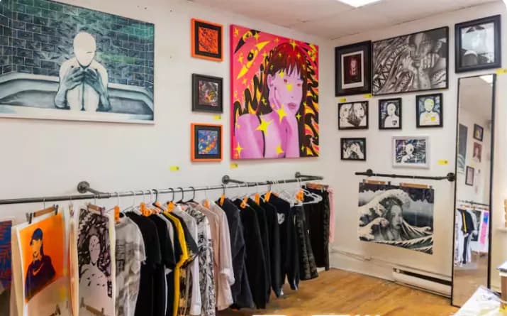 Des vêtements peints par des artistes, sur un portant dans la galerie.